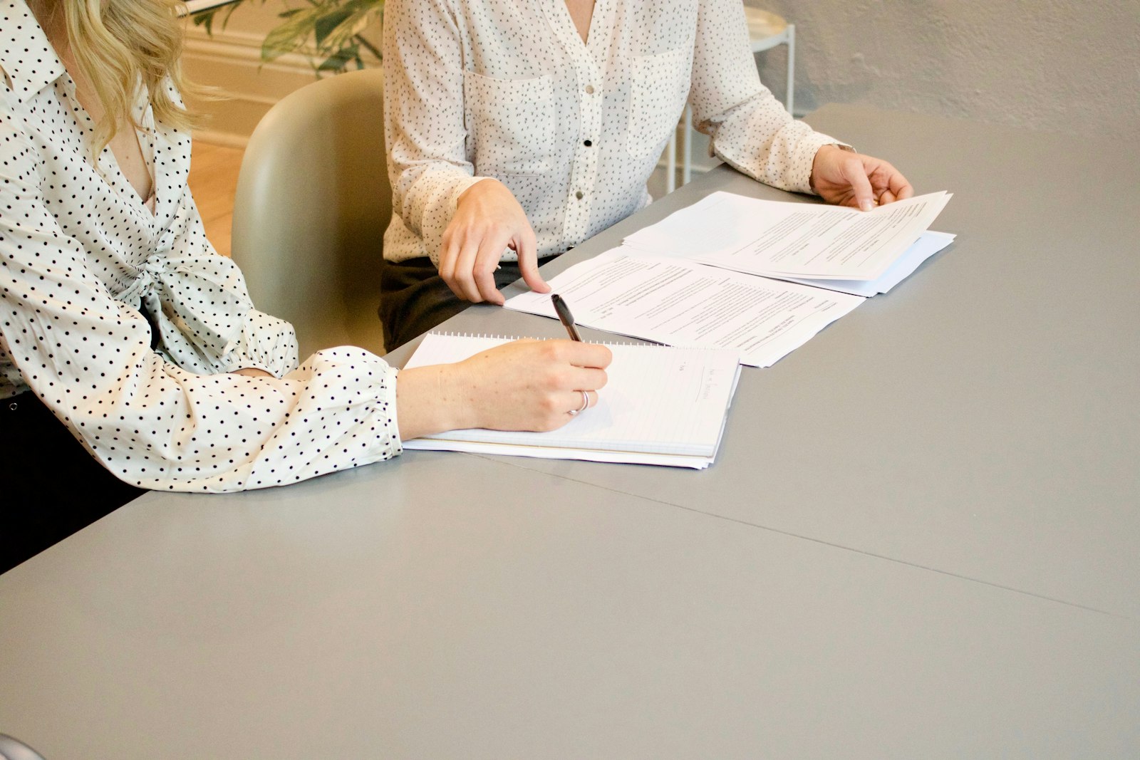 A person signing documents across a desk during a consultation