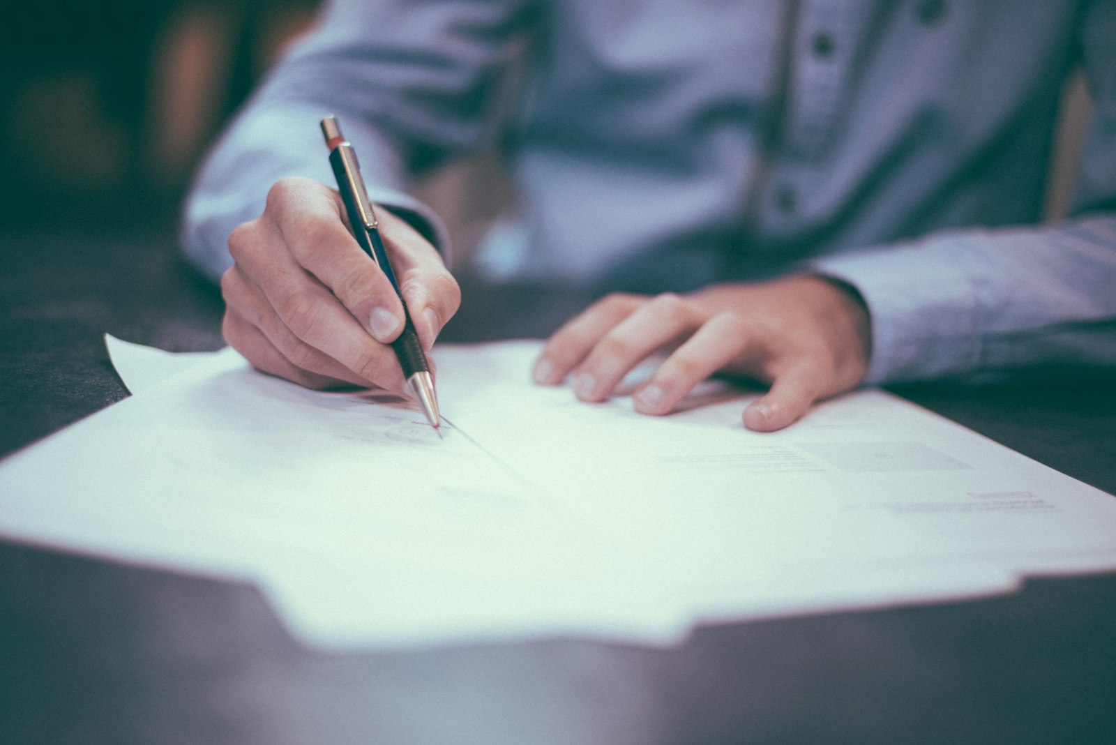 A person signing a paper contract at a table