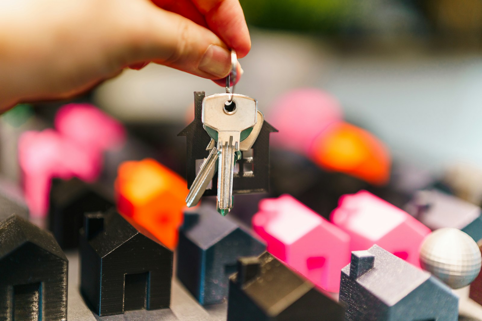 A hand holding house keys above model homes
