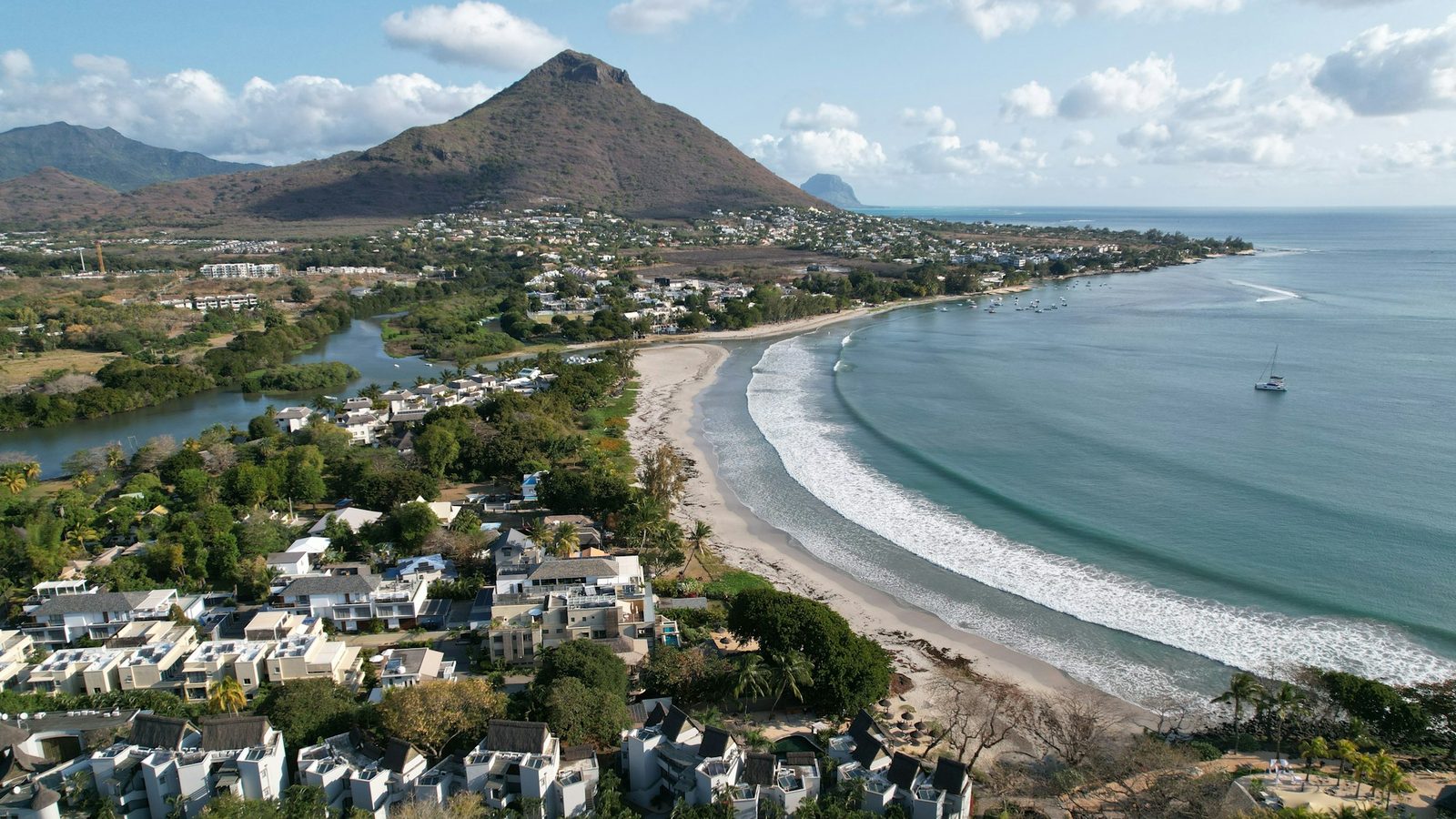 Vue aérienne de Tamarin sur la côte ouest de Maurice : maisons le long de la baie et montagne à l’arrière-plan